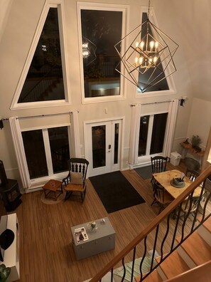 A multi-level interior with a staircase, a dining area with chairs and a table, and a chandelier.