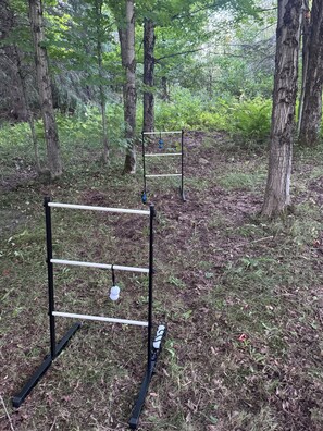 Two metal structures in a forested area with grass and trees.