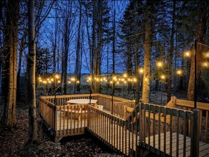 A wooden deck with a table and chairs, surrounded by trees.