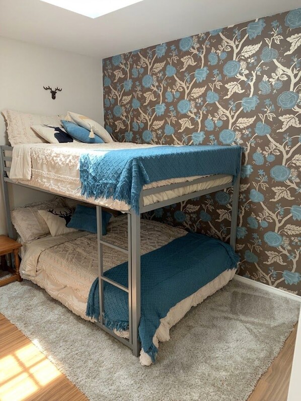 A bunk bed with a blue blanket, a patterned wall, and a deer head decoration.