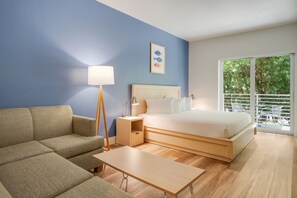 Ein modernes Hotelzimmer mit Bett, einer Couch, einem Nachttisch und einer Lampe.