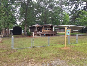 A lodge with a covered porch, a fenced-in grassy area, and a sign indicating a lake house.