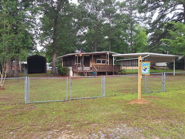 A lodge with a covered porch, a fenced-in grassy area, and a sign indicating a lake house. - Those Southern Nights can be memorable in Fort Gaines, GA (Fort Gaines)