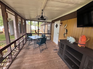 A covered outdoor area with a table and chairs, a ceiling fan, and a mounted television. - Those Southern Nights can be memorable in Fort Gaines, GA (Fort Gaines)