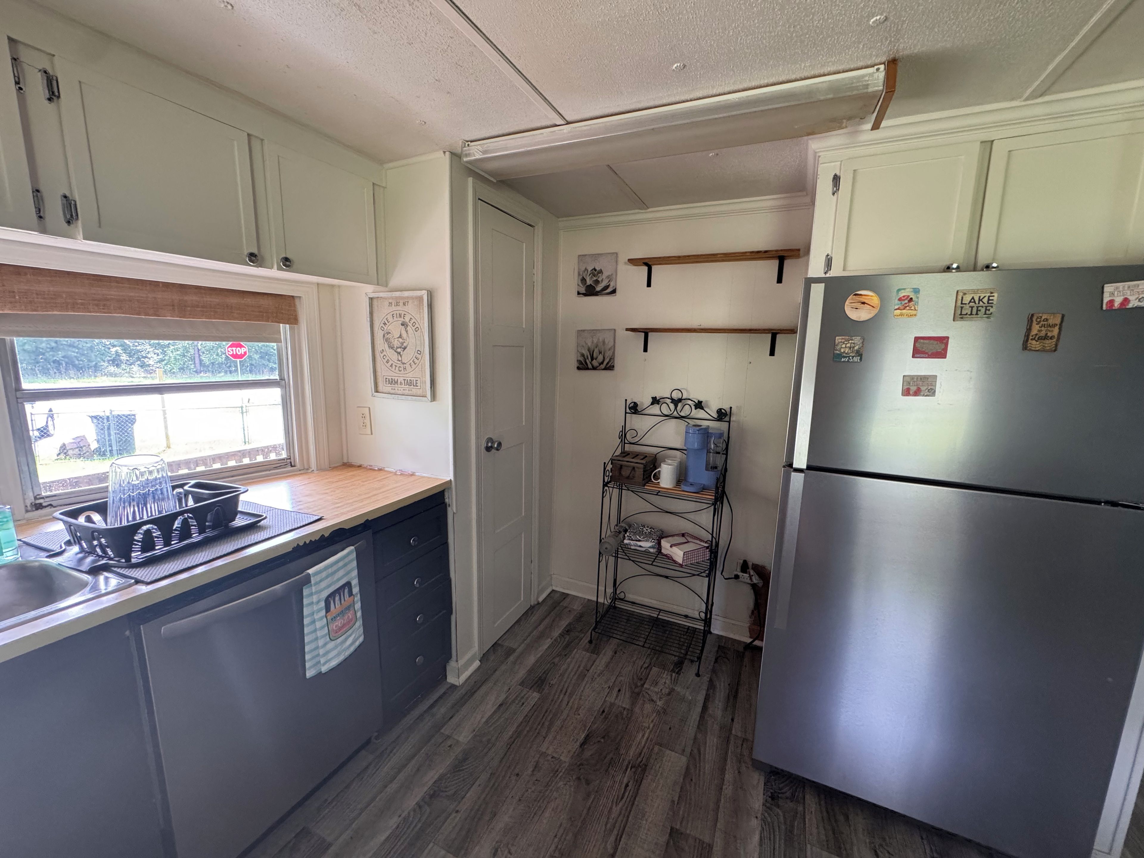 Una cocina compacta con refrigerador, lavamanos y ventana.