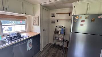 Una cocina compacta con refrigerador, lavamanos y ventana.