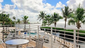 Terraza con piscina, palmeras y vista al océano.