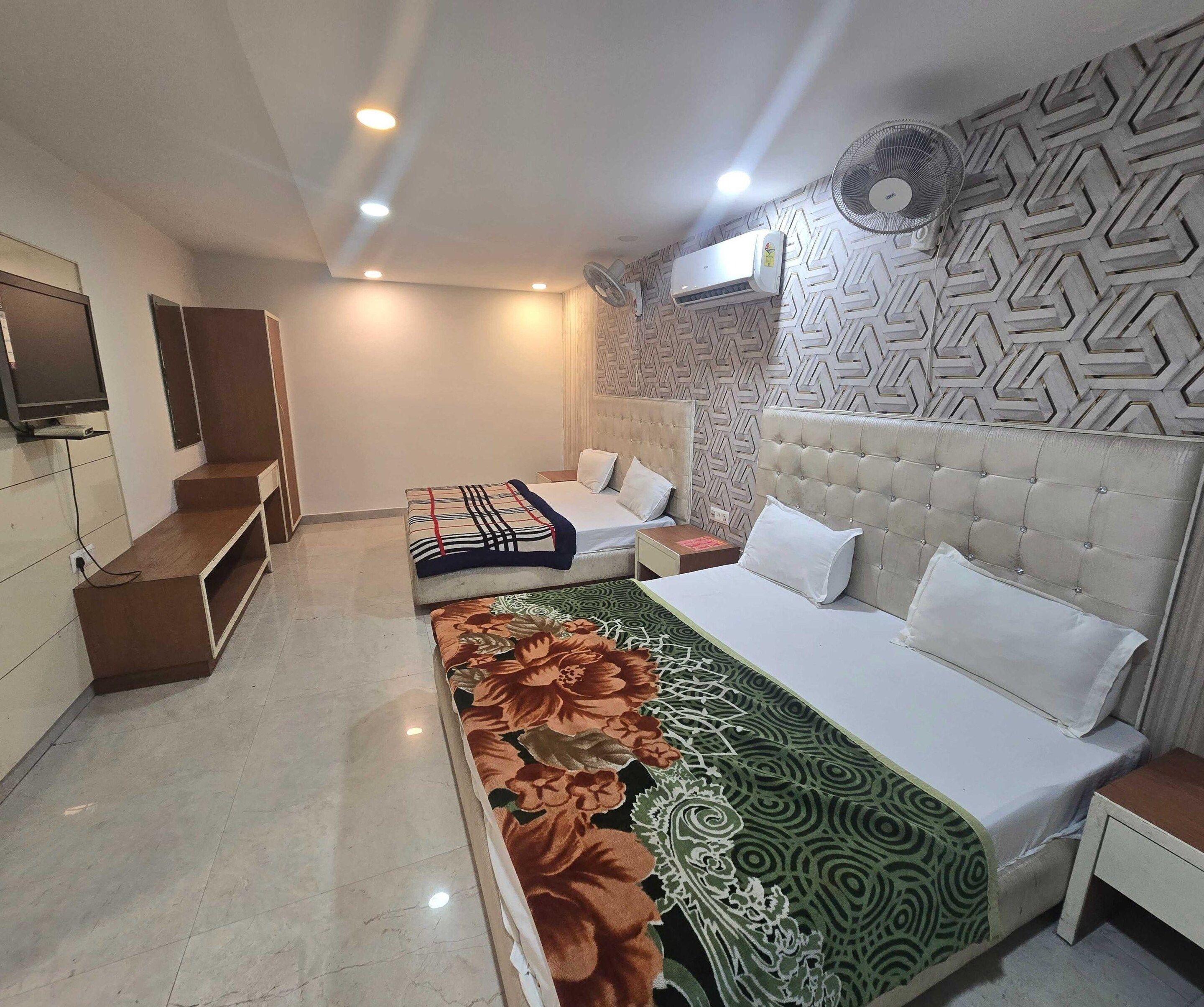 Una habitación de hotel con una cama, mesitas de noche, un televisor y un papel tapiz estampado.