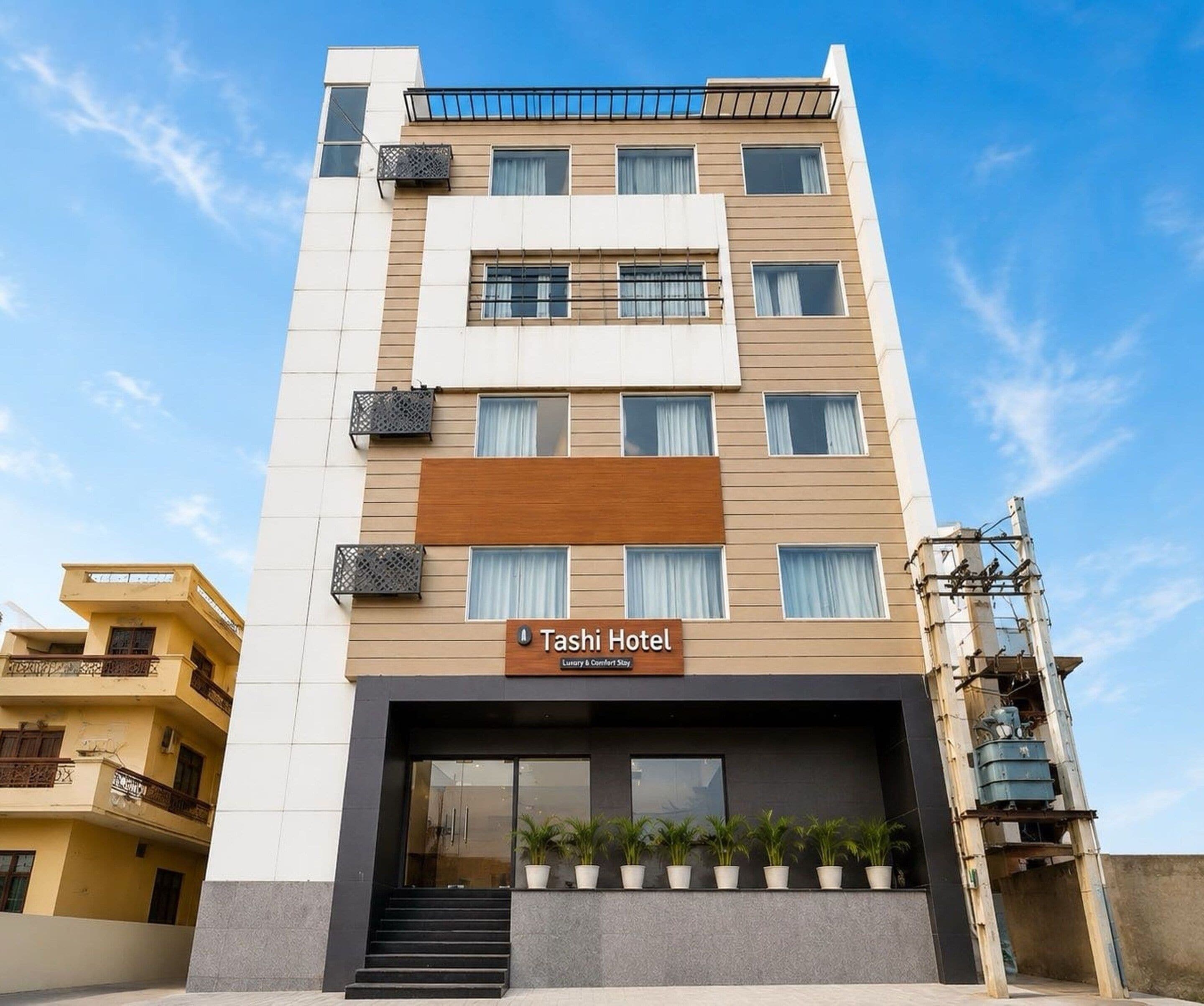 A multi-story hotel with a sign reading 'Tashi Hotel' indicating a luxury and comfort stay.