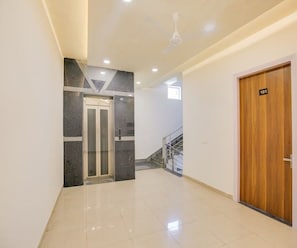 A hallway with a wooden door marked '101', a glass elevator, and a staircase. - Deluxe Room Hotel Tashi (Amritsar)
