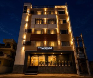 Ein mehrstöckiges Hotel mit einem Schild, auf dem 'Tashi Hotel' und 'Luxury & Comfort Stay' steht.