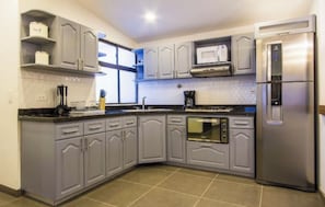 Eine moderne Küche mit grauen Schränken, einem Edelstahl-Kühlschrank, einer Mikrowelle und einem eingebauten Backofen.
