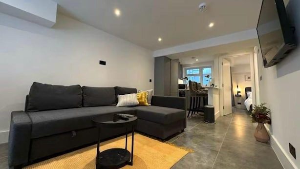 Un salon moderne avec un canapé, une table basse et un téléviseur à écran plat fixé au mur.