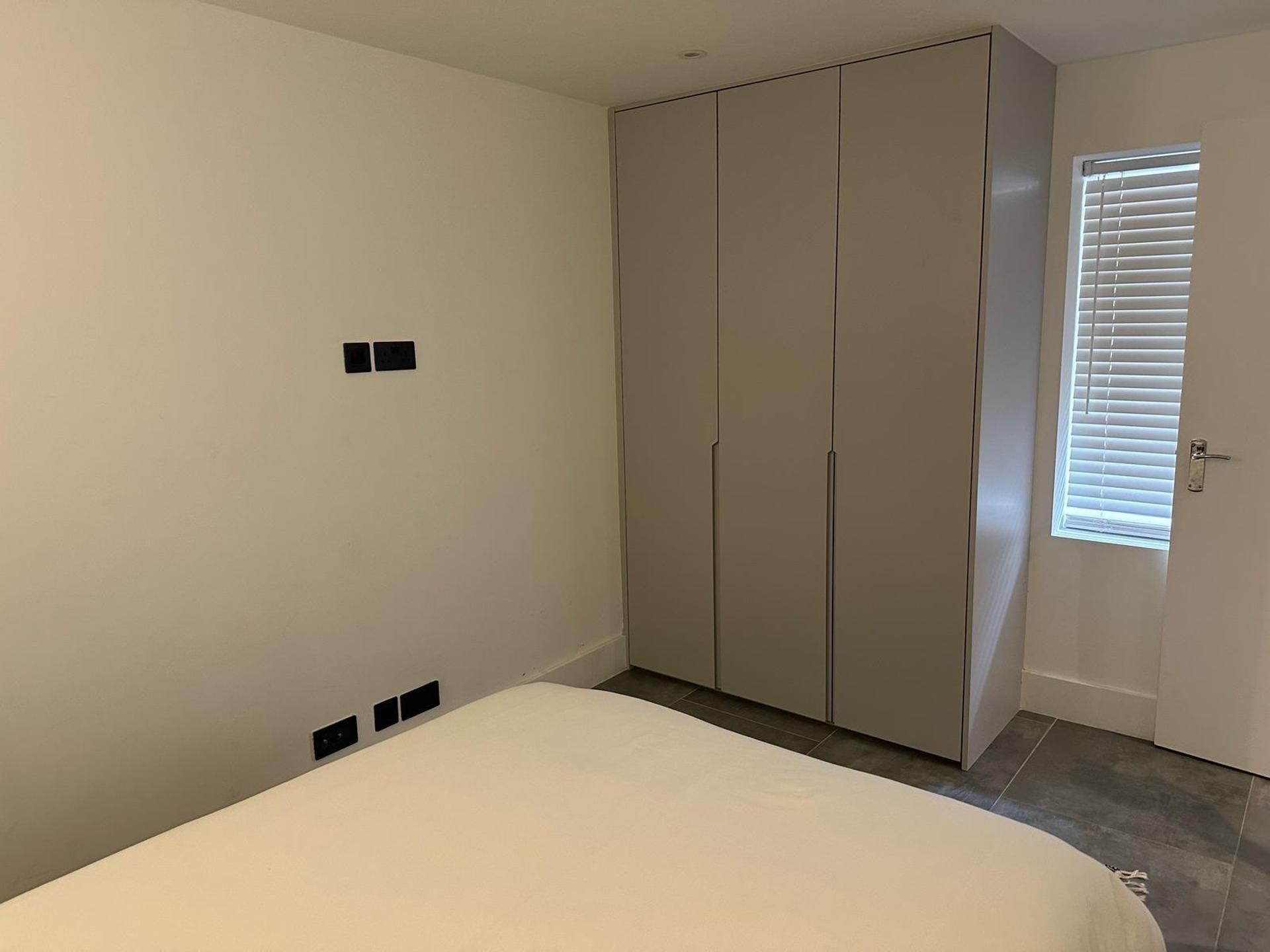 Een slaapkamer met een bed, een kledingkast en een deur voorzien van zonwering.