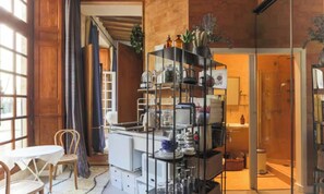 A kitchen with a central island, a dining area with a table and chairs, and a glass door leading to a bathroom. - CENTRAL PARIS APARTMENT WITH PRIVATE BEDROOM, 2 BATHROOMS & INNER COURTYARD VIEW (Paris)