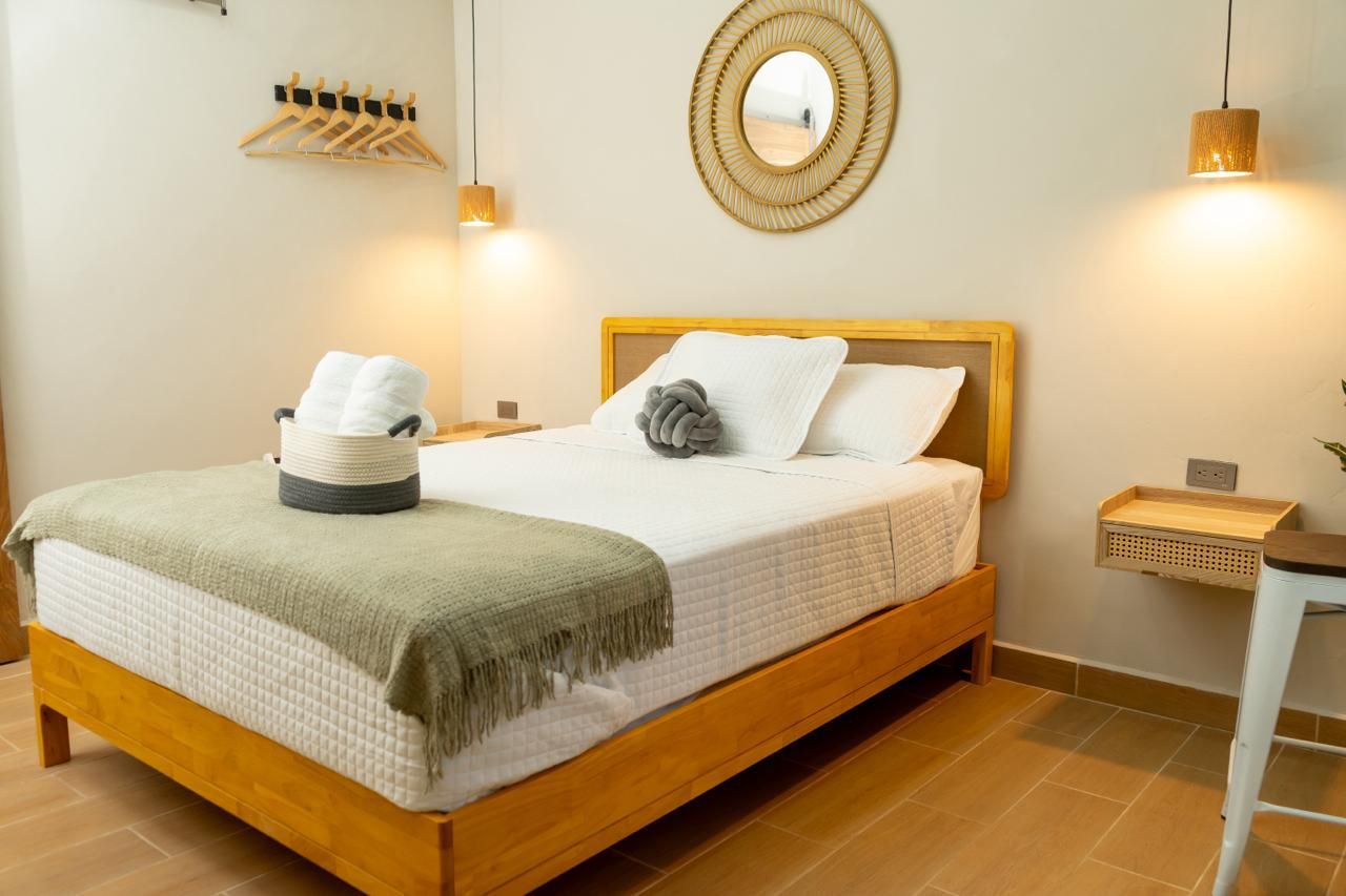 A neatly made bed with a green throw blanket, a white pillow, and a towel on a wooden headboard.