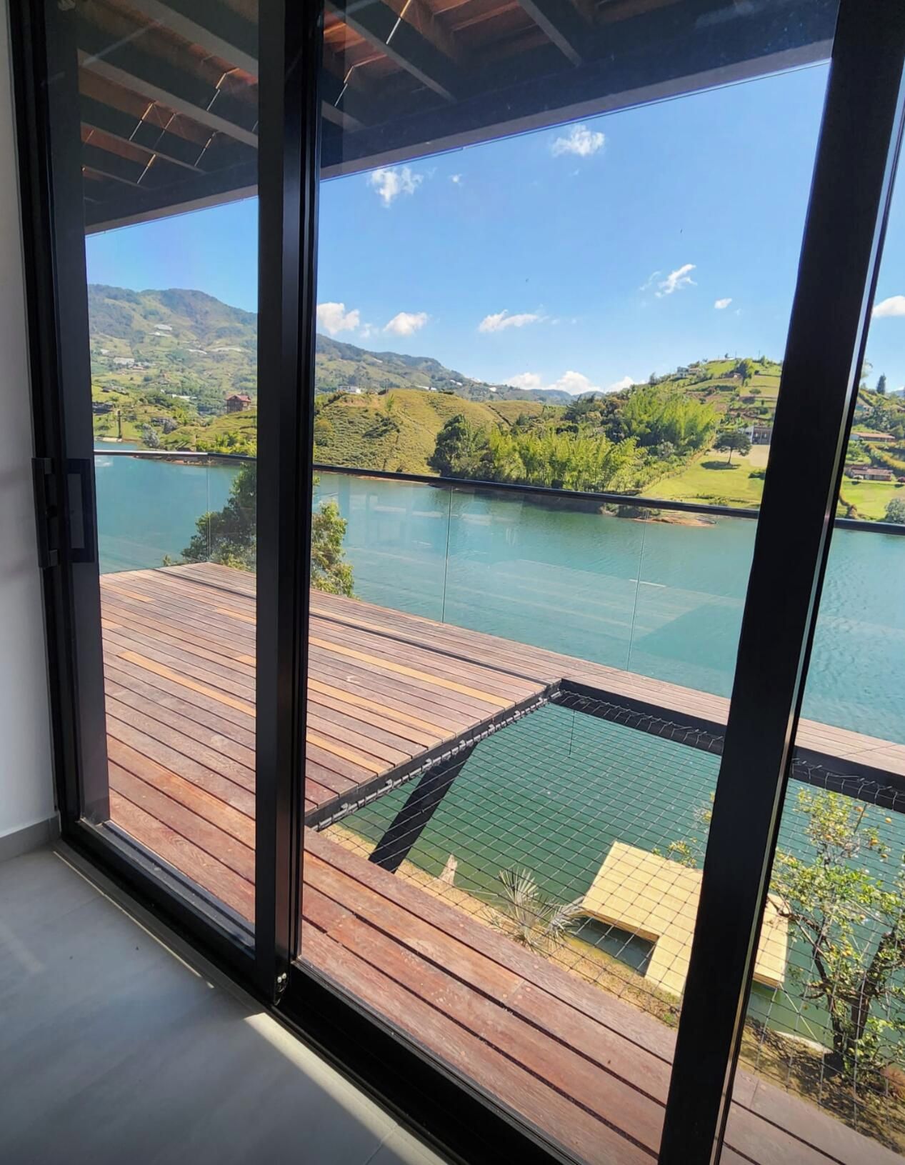 A view from a room with large windows overlooking a lake and hills.