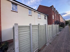 A residential street with houses, a wooden fence, and a paved walkway. - Cosy coach house in Hereford (Hereford)
