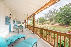 A covered outdoor seating area with a wooden railing, a table, and chairs. - Renovated Horse Corral Hideaway (Santa Fe)