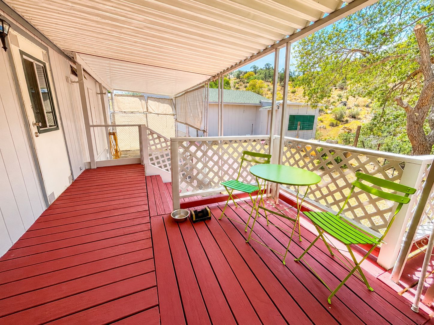 A covered outdoor area with a red wooden floor, a green table, and a bench.