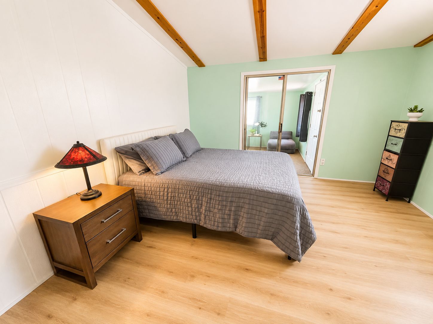 Une chambre à coucher comprenant un lit, une table de chevet, une lampe, une commode et une autre commode avec des tiroirs.