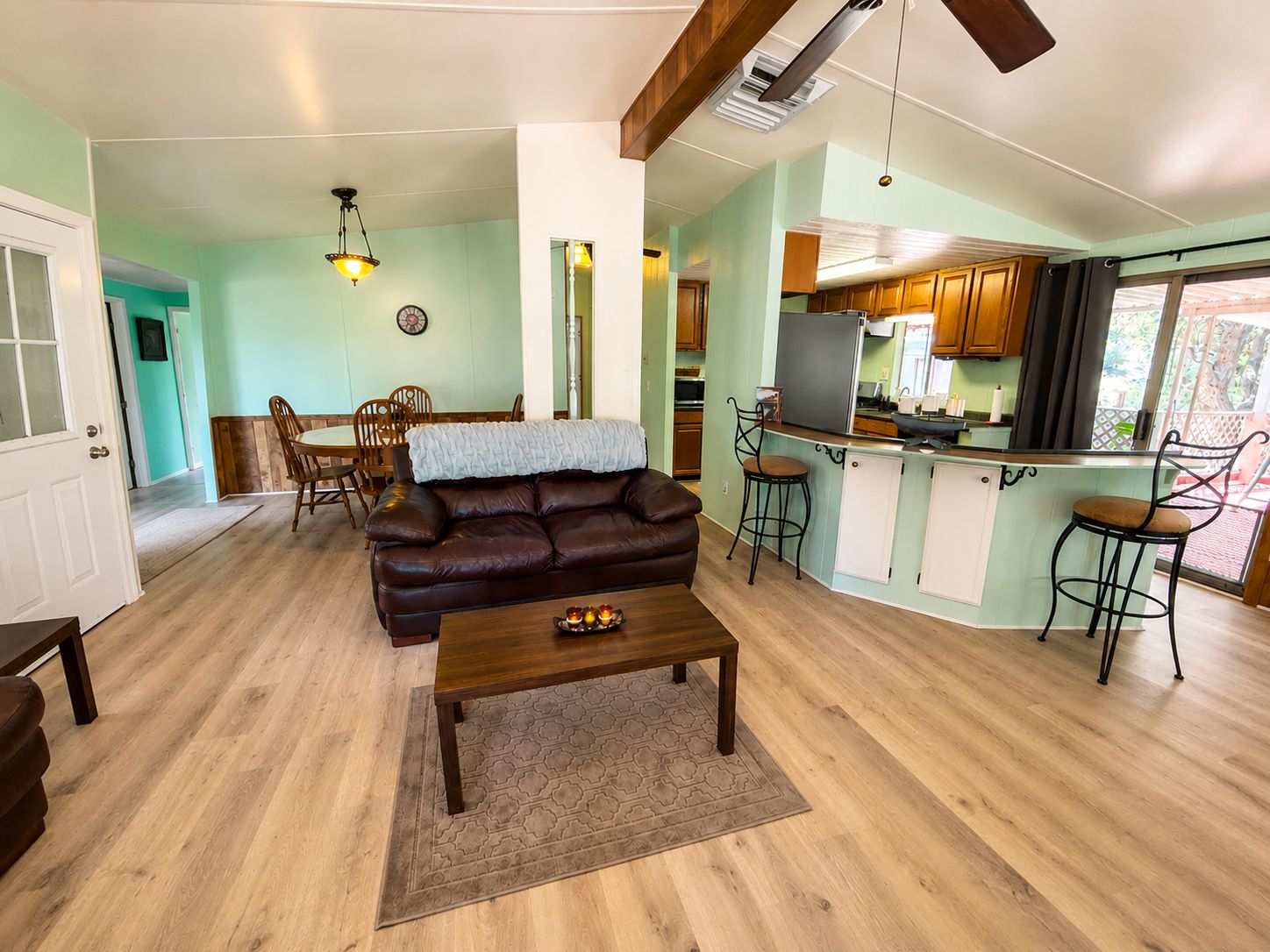 Ein Wohnzimmer mit braunem Ledersofa, einem Holztisch und einem Essbereich mit Holztisch und Stühlen.