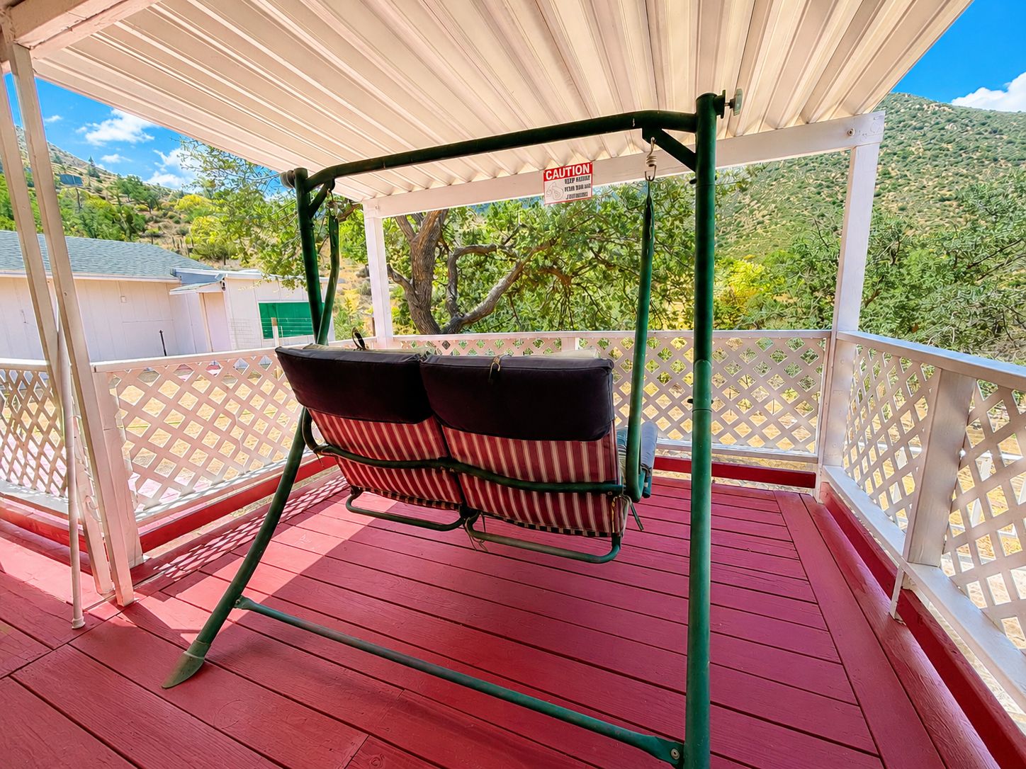 A covered outdoor seating area with a swing chair and a caution sign.