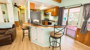 A kitchen with wooden cabinets, a bar area with stools, and a view of the outdoors.