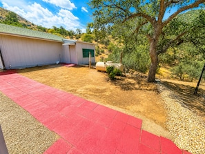 A building with a red paved area, a green door, and a tree in the background.
