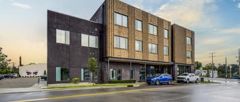 A modern building with a flat roof, large windows, and a parking lot.