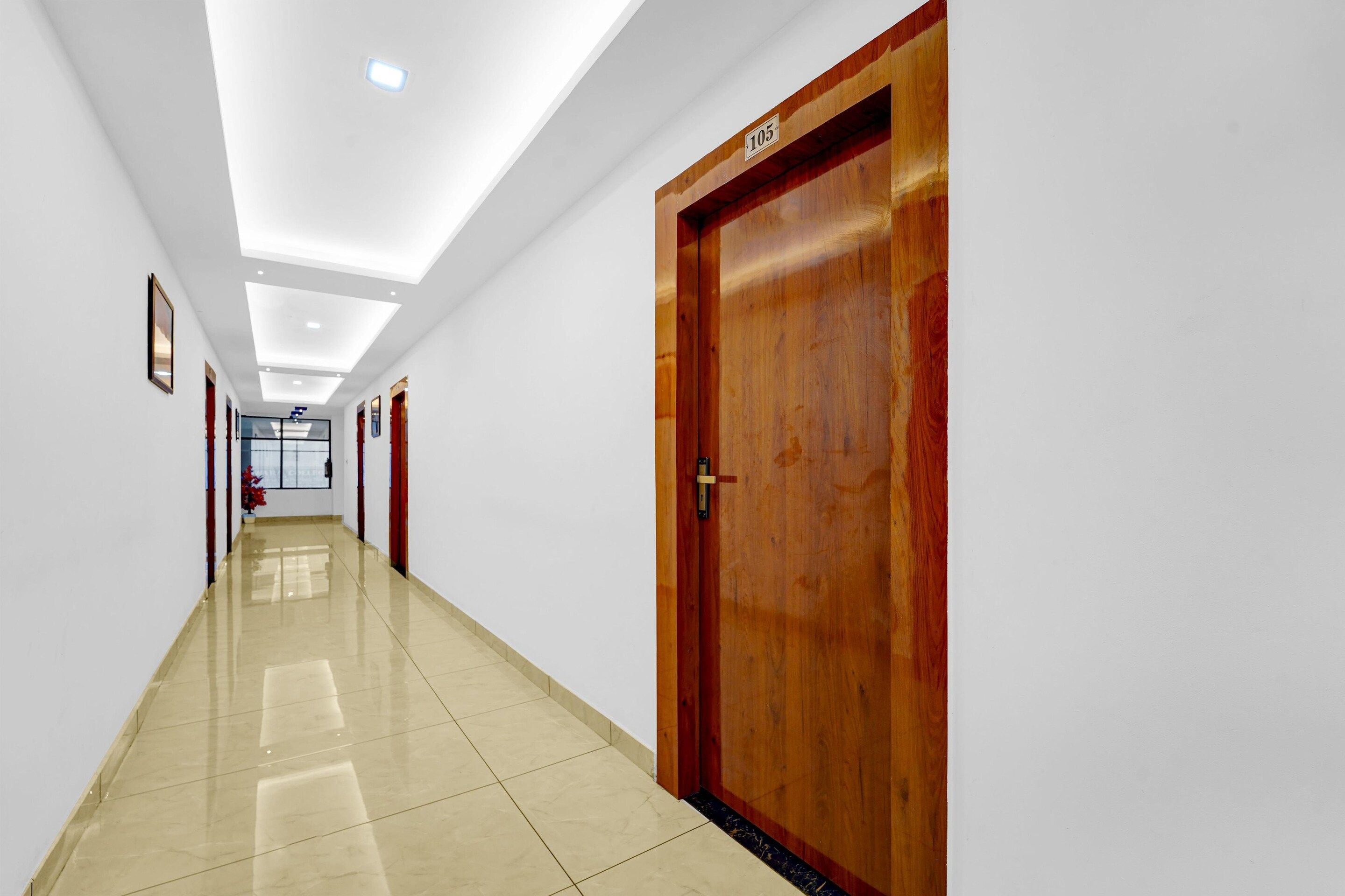A hallway with a wooden door labeled '105', white walls, and a tiled floor.