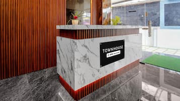 A reception desk with a marble top, a sign indicating 'TOWNHOUSE' and 'oyo-Serviced', and a wooden panel design.