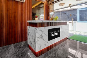 Una recepción con encimera de mármol, un cartel que indica 'TOWNHOUSE' y 'oyo-Serviced', y un diseño de paneles de madera.