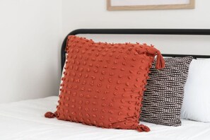 Ein Bett mit einem roten, strukturierten Kissen und einem Kissen mit Punkten.