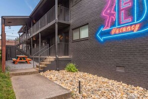 A building with a neon sign indicating vacancy, outdoor seating, and a staircase leading to an upper level. - The Lyric - #101 & #102 | Two Suites on Music Row (Nashville)