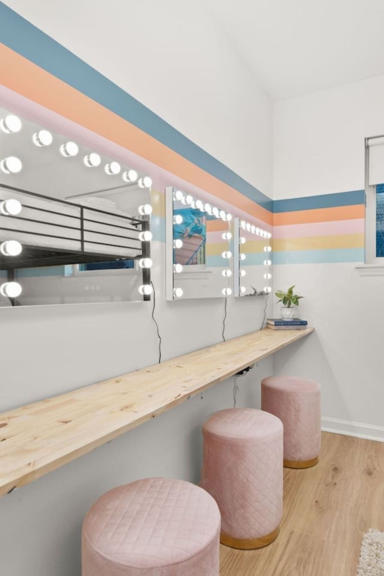 Een badkamer met een wastafel, spiegels en een plankje met een plant.