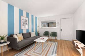 Una sala de estar moderna con un sofá, una mesa de centro, dos sillones, un televisor y una puerta.