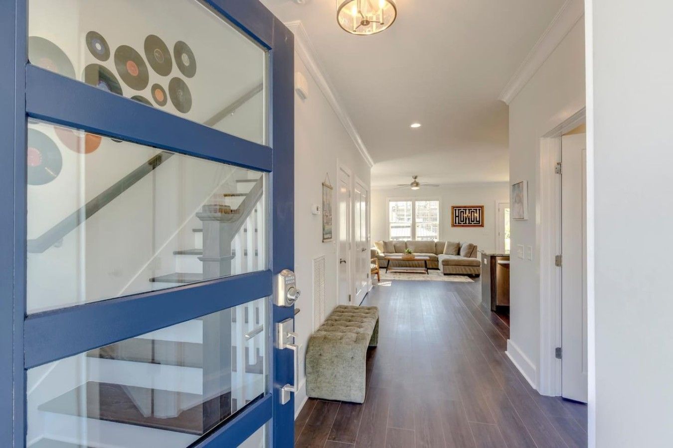 Un couloir avec une porte bleue, un escalier, un canapé et une table basse.