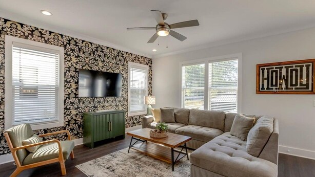 Un salon comprenant un canapé, un fauteuil, une table basse, un téléviseur et un ventilateur de plafond.