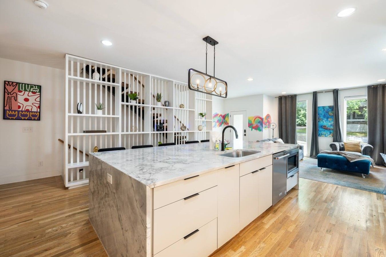 Een moderne keuken met een marmeren eiland, witte kasten en een inbouw trap.