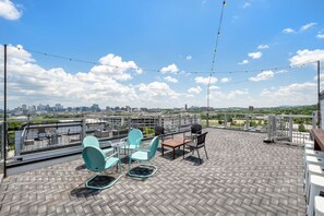 Een terras op het dak met zitplaatsen buiten, uitzicht op de stadshemel en een heldere lucht.