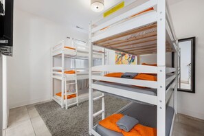 Een slaapkamer met stapelbed, grijs tapijt en een schilderij aan de muur.