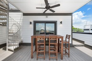 A covered outdoor area with a table and chairs, a ceiling fan, and a view of the sky. - Last Call Lounge | Rooftop Skyline + Game Room (Nashville)
