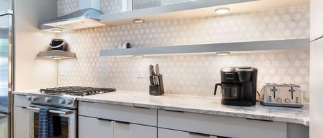 A modern kitchen with a gas stove, oven, coffee maker, and toaster.