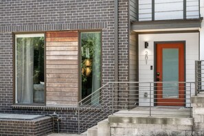 A modern building with a brick facade, large windows, and a red door. - Last Call Lounge | Rooftop Skyline + Game Room (Nashville)