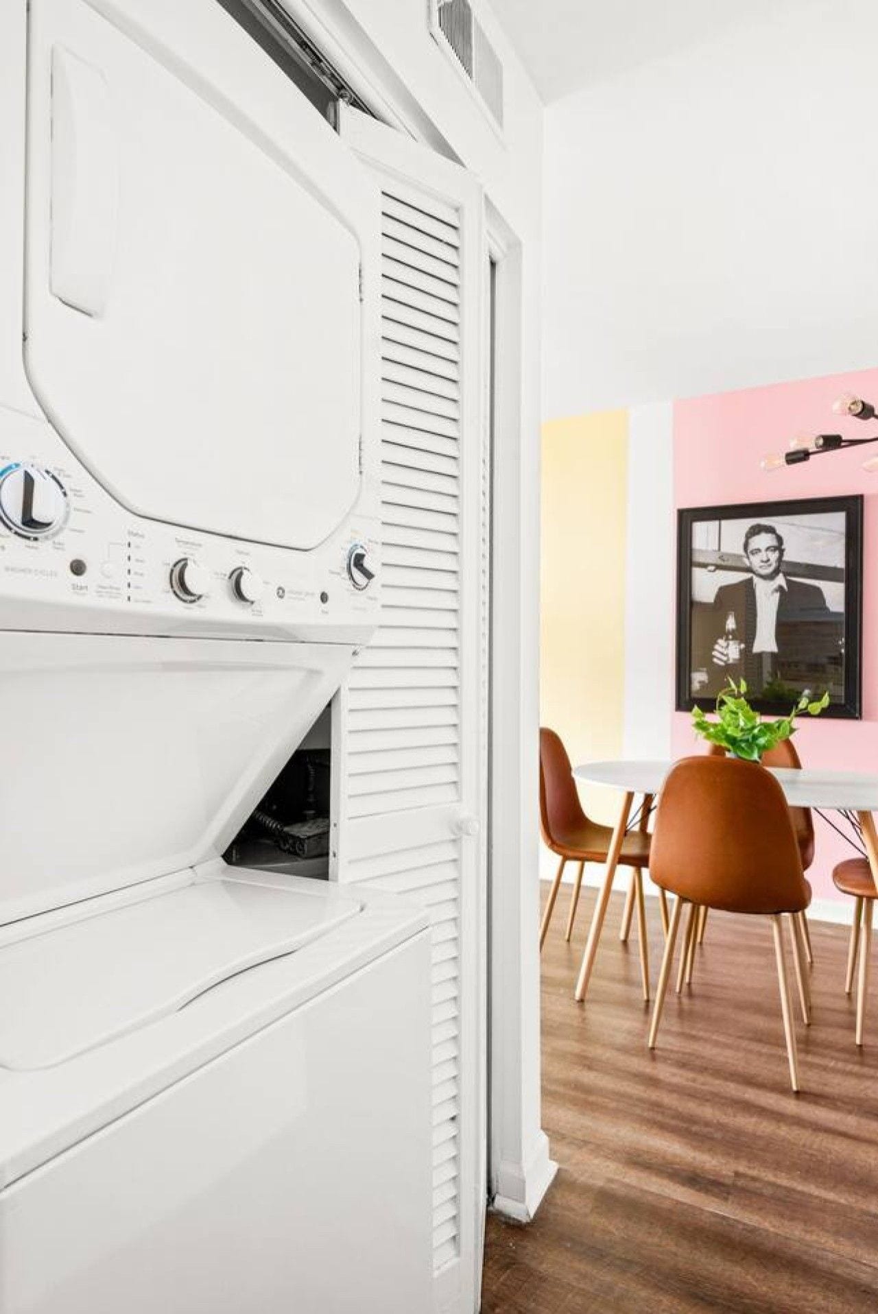 Eine moderne Küche mit einem weißen Herd, einem Essbereich mit Holzkreislern und einer rosa Wand.