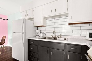A modern kitchen with white cabinets, a double sink, and a refrigerator. - The Lyric - #201 & #202 | Two Suites on Music Row (Nashville)