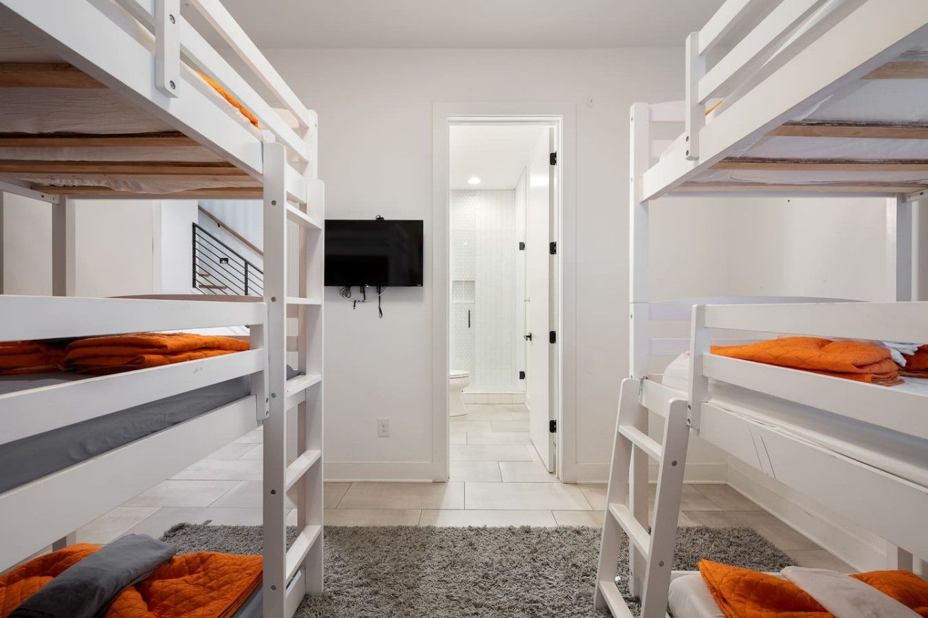 Une chambre avec des lits superposés, une télévision et une porte donnant sur une autre pièce.