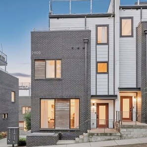 Een modern meerlaags woongebouw met een bakstenen gevel, grote ramen en een zichtbaar huisnummer.