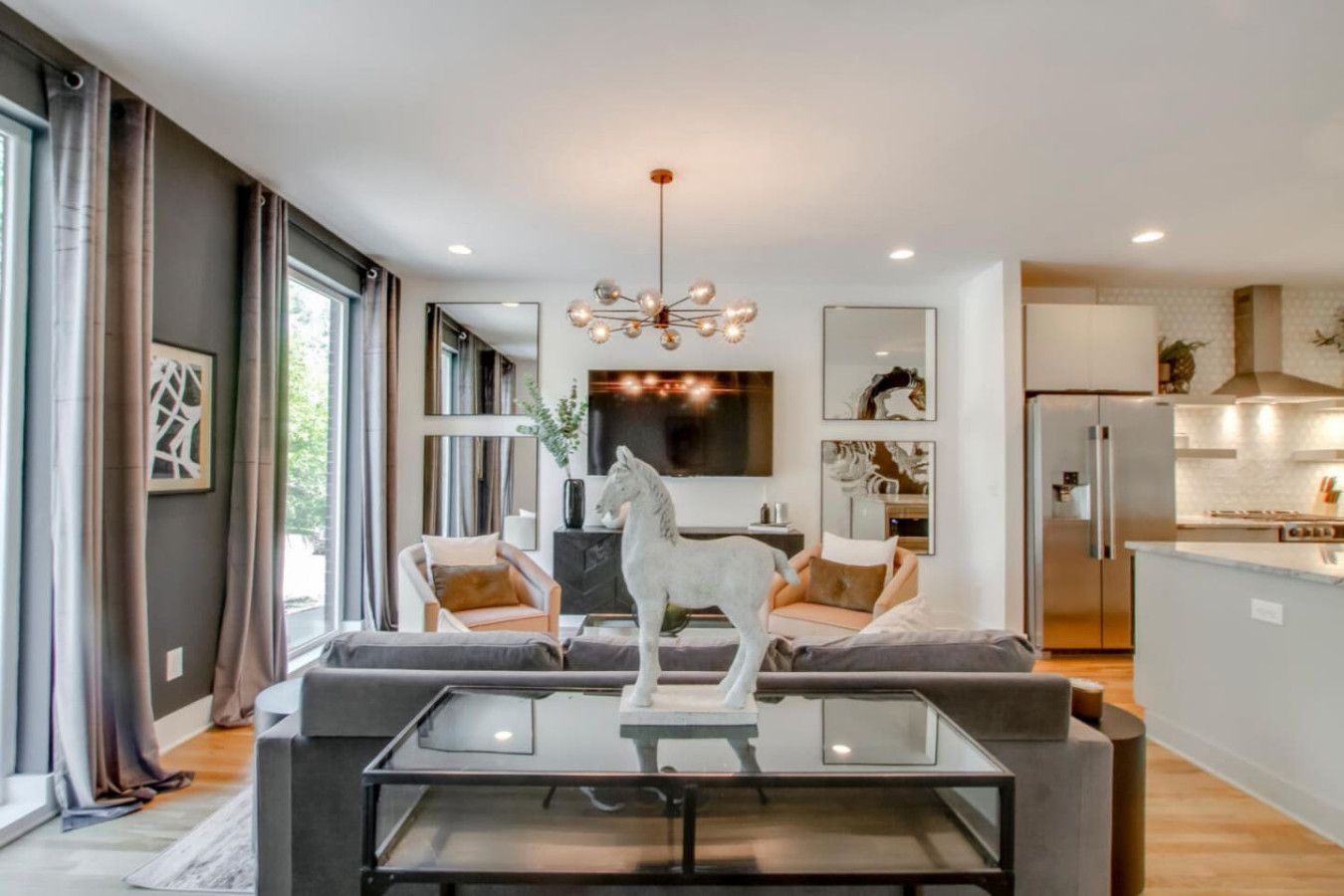 A modern living room with a glass coffee table, a sofa, and a mounted TV.